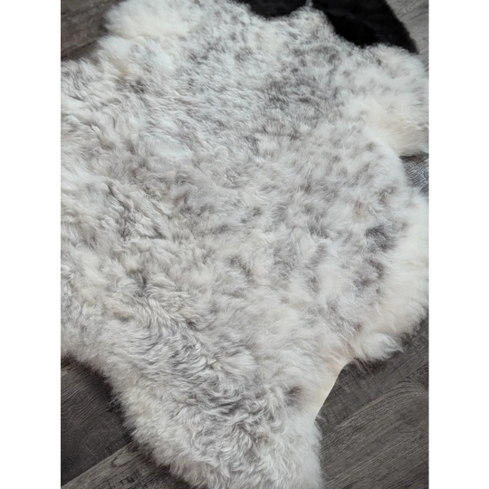 A soft large icelandic sheepskin rug with a fluffy medium spotted white and gray natural wool pattern