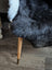 Black and white icelandic sheepskin throw with short wool draped over a wooden chair leg with brass metal cap