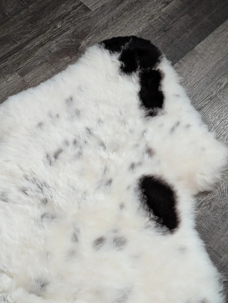 A large spotted icelandic sheepskin rug in white and black with soft fluffy faux fur texture perfect for cozy spaces