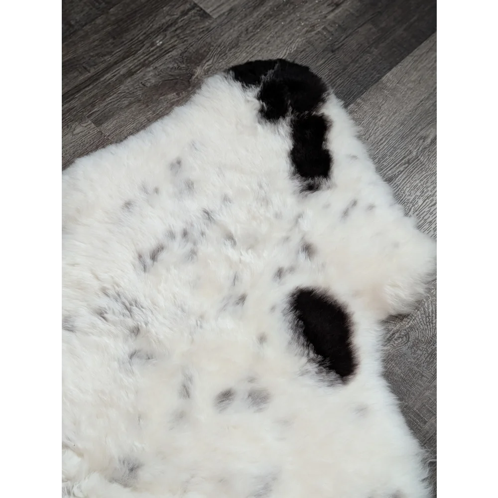 A large spotted icelandic sheepskin rug in white and black with soft fluffy faux fur texture perfect for cozy spaces