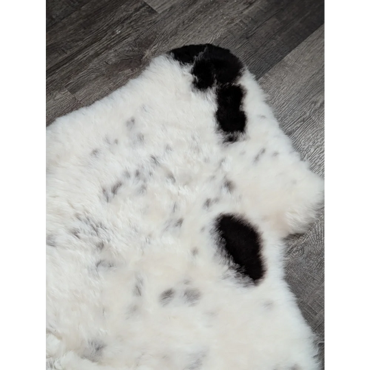 A large spotted icelandic sheepskin rug in white and black with soft fluffy faux fur texture perfect for cozy spaces