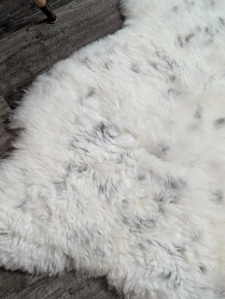 Large spotted icelandic sheepskin rug with soft white fluffy texture and subtle gray speckles made of short wool