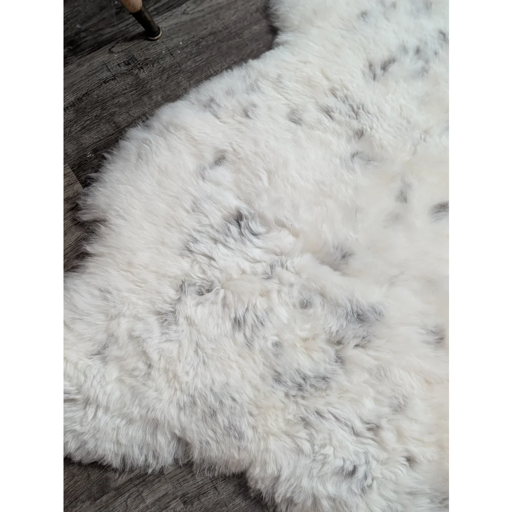 Large spotted icelandic sheepskin rug with soft white fluffy texture and subtle gray speckles made of short wool
