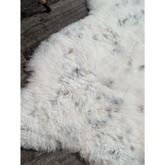 Large spotted icelandic sheepskin rug with soft white fluffy texture and subtle gray speckles made of short wool