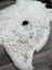 A plush white large spotted icelandic sheepskin rug with a black spot made of short wool measuring 45 by 29 inches