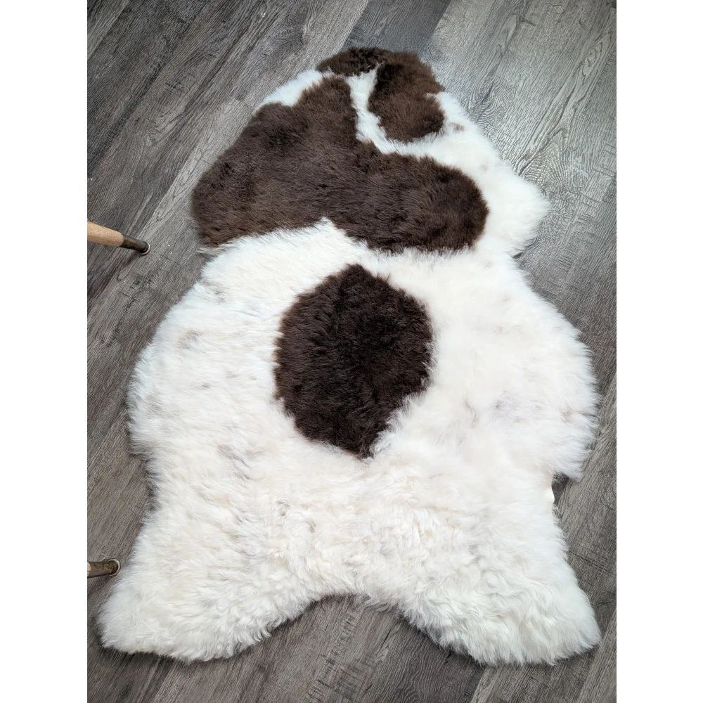 A large plush white and brown medium spotted icelandic sheepskin rug with soft fluffy short wool texture