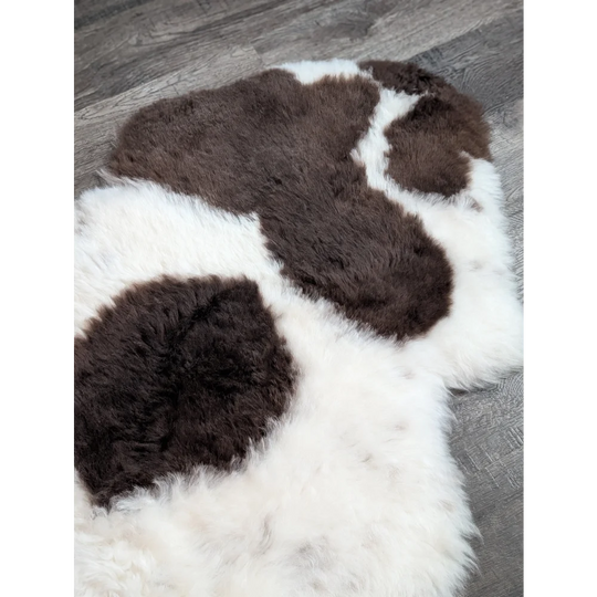 A large plush spotted icelandic sheepskin rug with natural brown and white cow print short wool fibers