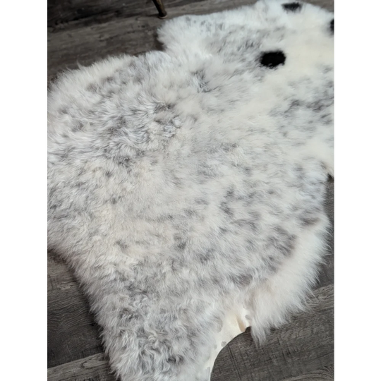 A large spotted icelandic sheepskin rug with soft white and gray speckled fluffy wool for cozy decor