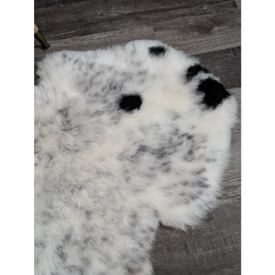 A large plush spotted icelandic sheepskin rug in white and black with soft fluffy texture for cozy decor