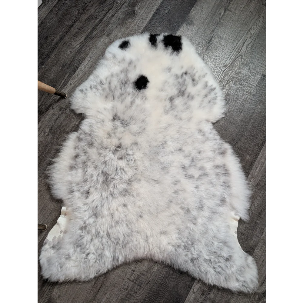 A plush large icelandic sheepskin rug in white and gray with three black spots perfect as a medium spotted icelandic decor
