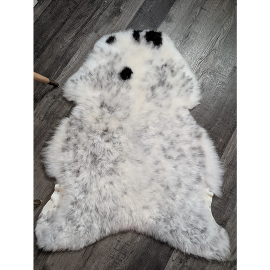 A plush large icelandic sheepskin rug in white and gray with three black spots perfect as a medium spotted icelandic decor