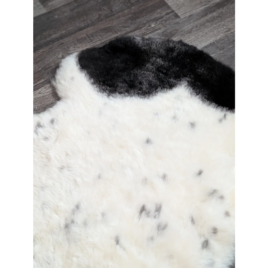 A plush white and black medium spotted icelandic sheepskin rug with soft fluffy texture 45 by 30 inches
