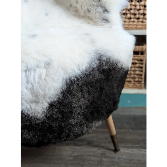 A plush spotted icelandic sheepskin throw blanket in gradient white to black with soft natural wool texture and 45 by 30 size