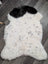 A large 45 x 30 inch medium spotted icelandic sheepskin rug with white wool, black patch, and dark speckles
