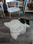 A fluffy white and black medium spotted icelandic sheepskin rug with natural fur texture lying on the floor