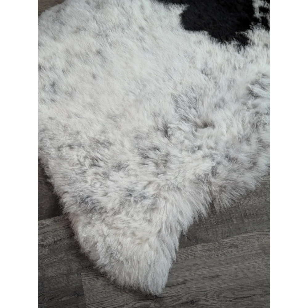 A large spotted icelandic sheepskin rug in white and black with soft fluffy short wool perfect for cozy spaces