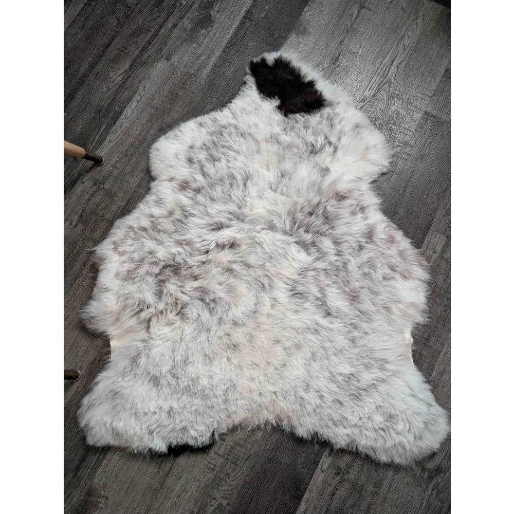 A plush 43 x 33 inch large spotted icelandic sheepskin rug with soft white gray fur and a distinct black patch on top