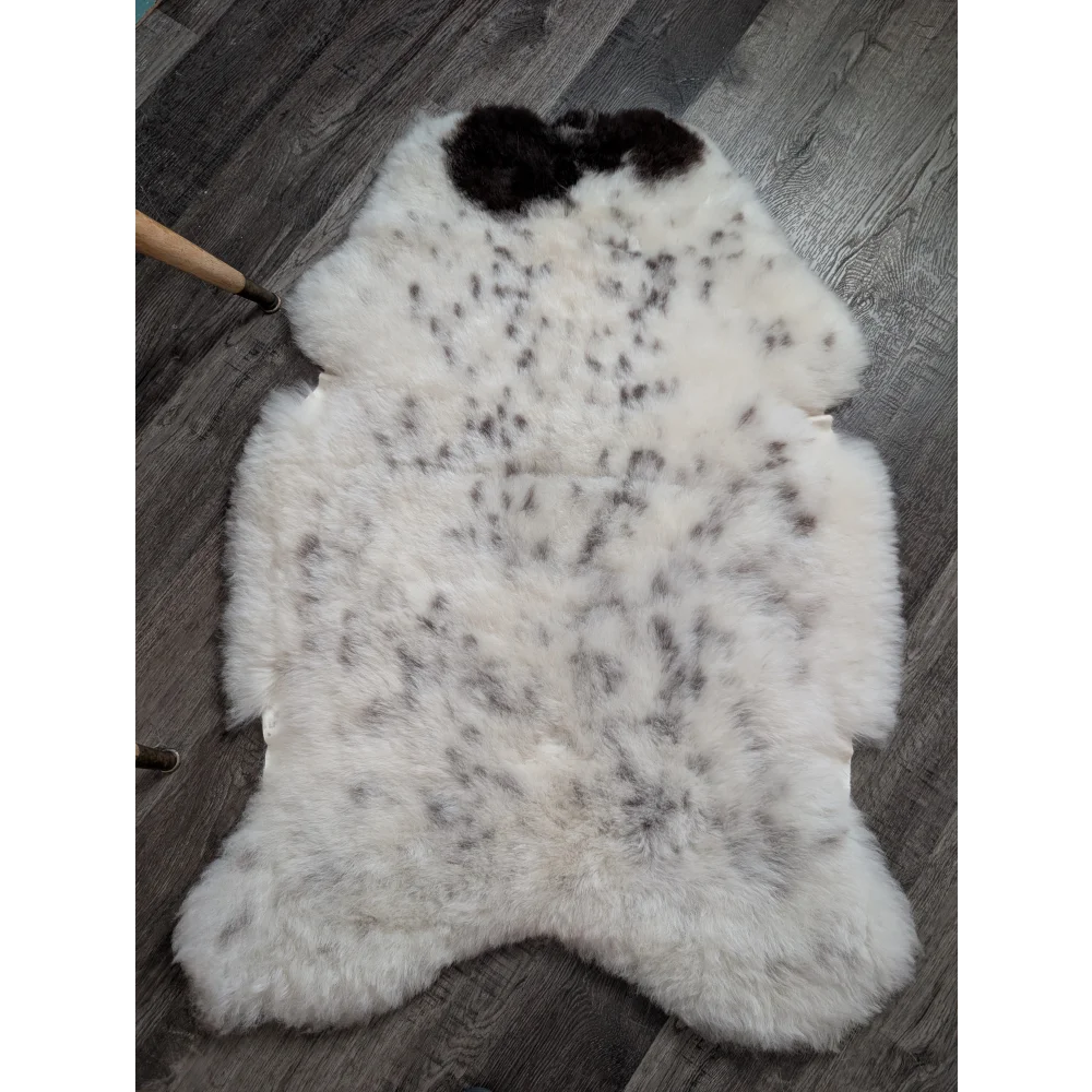 White spotted icelandic sheepskin rug with black and gray speckles fluffy natural shape medium spotted icelandic wool