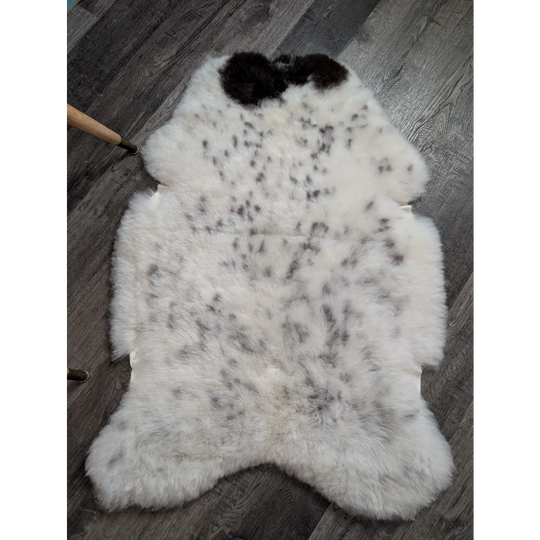 White spotted icelandic sheepskin rug with black and gray speckles fluffy natural shape medium spotted icelandic wool