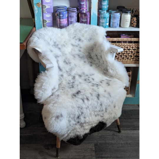 A plush white and black speckled sheepskin chair cover made from soft spotted icelandic sheepskin wool