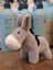 A soft plush gray donkey toy with white muzzle and black saddle called the donkey perfect for kids and collectors