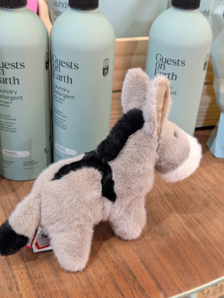 A soft plush donkey toy called the donkey with gray and black fur and white accents on its muzzle and ears
