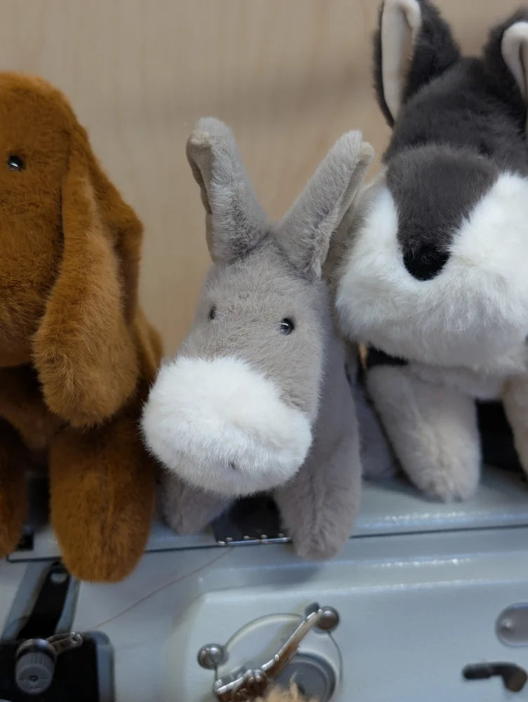 A gray plush donkey with a white muzzle and black button eyes called the donkey stuffed animal toy