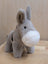 The donkey soft gray plush donkey with white muzzle and black eyes standing on a wooden surface