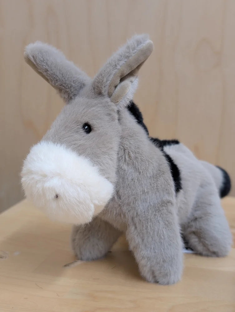 A soft gray plush donkey called the donkey with a white muzzle and black markings on its fluffy back