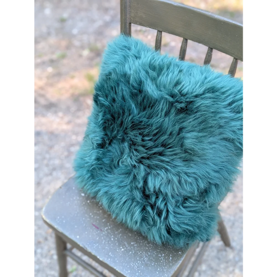 The green cushion is a plush teal dyed green faux fur throw pillow with a soft shaggy texture from angus oliver
