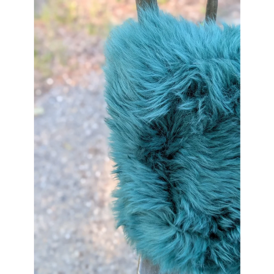 The green cushion plush teal faux fur ear warmer with soft dense texture and slightly frayed edges dyed green