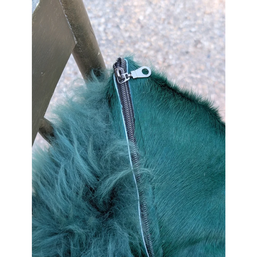 The green cushion with a teal faux fur zipper pull on dyed green fluffy fabric inspired by angus oliver cowhide