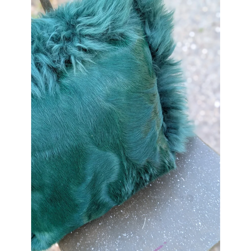 The green cushion emerald green faux fur clutch with dyed green plush textured surface and slightly frayed edges