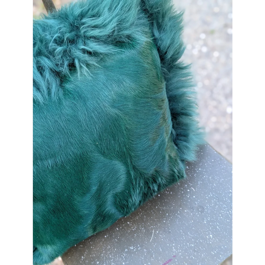 The green cushion emerald green faux fur clutch with dyed green plush textured surface and slightly frayed edges