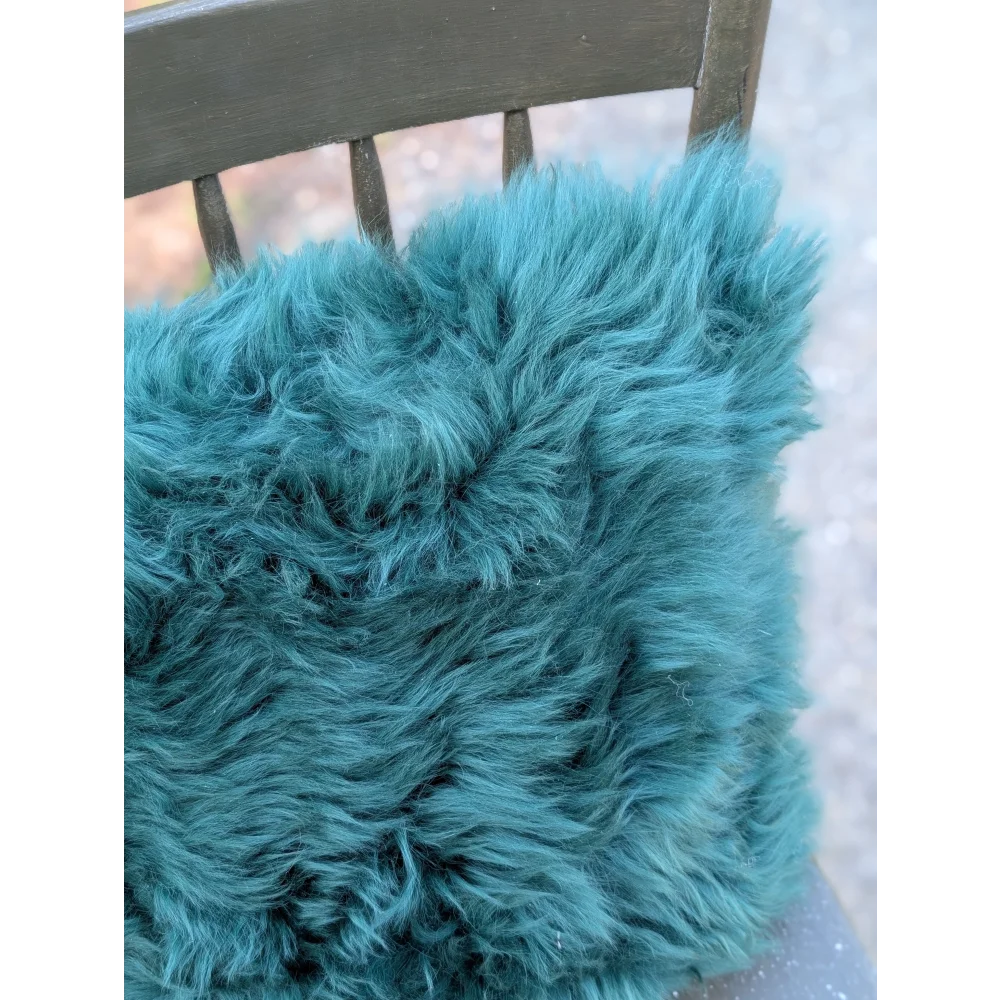 A plush teal dyed green cushion with soft fluffy faux fur texture perfect for cozy home decor by angus oliver