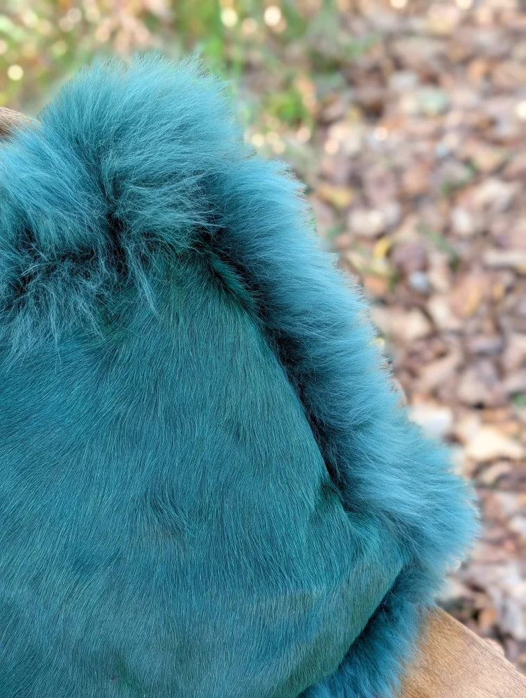 A plush teal woolly green faux fur hat with soft fluffy texture perfect for a cozy sewing studio vibe