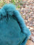 A plush teal woolly green faux fur hat with soft fluffy texture perfect for a cozy sewing studio vibe