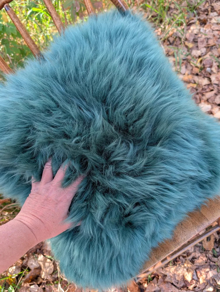 A plush teal green sheepskin throw with soft woolly green texture perfect for a cozy sewing studio space