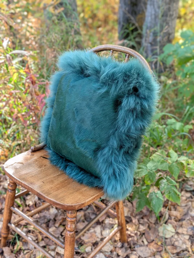 Teal faux fur backpack with plush fluffy texture and soft dense fibers inspired by green sheepskin from sewing studio