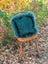 A plush teal woolly green sheepskin and cowhide cushion with fluffy texture on an old wooden chair in a sewing studio