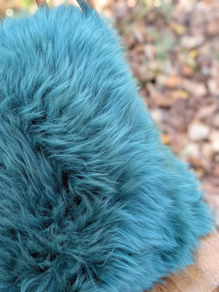 A plush teal woolly green faux fur blanket perfect for cozying up in your sewing studio or living space