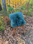 A plush green sheepskin and cowhide cushion with woolly green faux fur on a wooden chair in a sewing studio