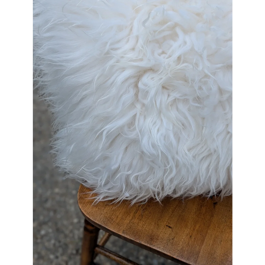 A plush white moo cushion pillow with long wool curly fibers perfect for cozy home decor and sewing machines use