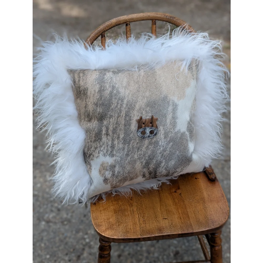 A cozy moo cushion square pillow with gray white cowhide patchwork plush long wool trim and rustic wooden button center