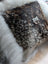 The moo cushion features a decorative cow-shaped brooch with blue eyes and a textured dark brown and white hide finish