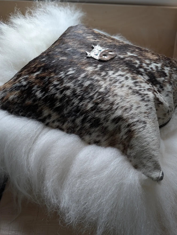 The moo cushion is a square cushion in natural brown and white cowhide with a silver animal charm perfect for angus oliver fans
