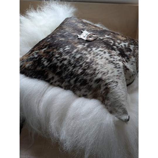 The moo cushion is a square cushion in natural brown and white cowhide with a silver animal charm perfect for angus oliver fans