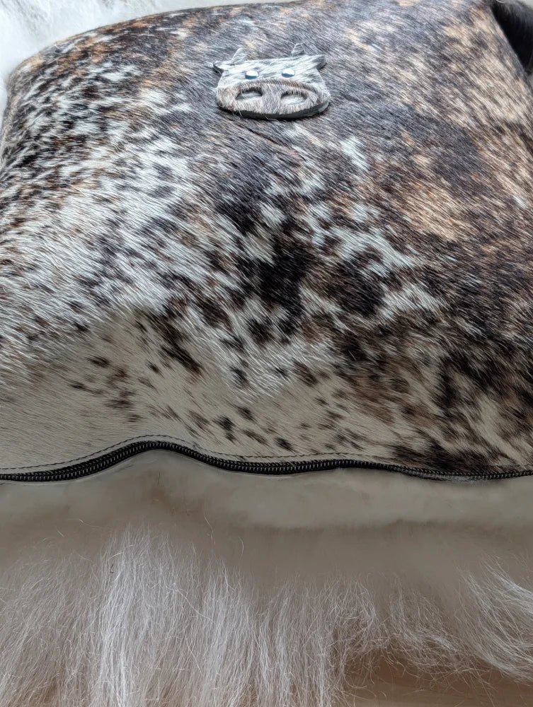 The moo cushion is a brown and white spotted cowhide clutch with a silver pig emblem perfect for angus oliver fans