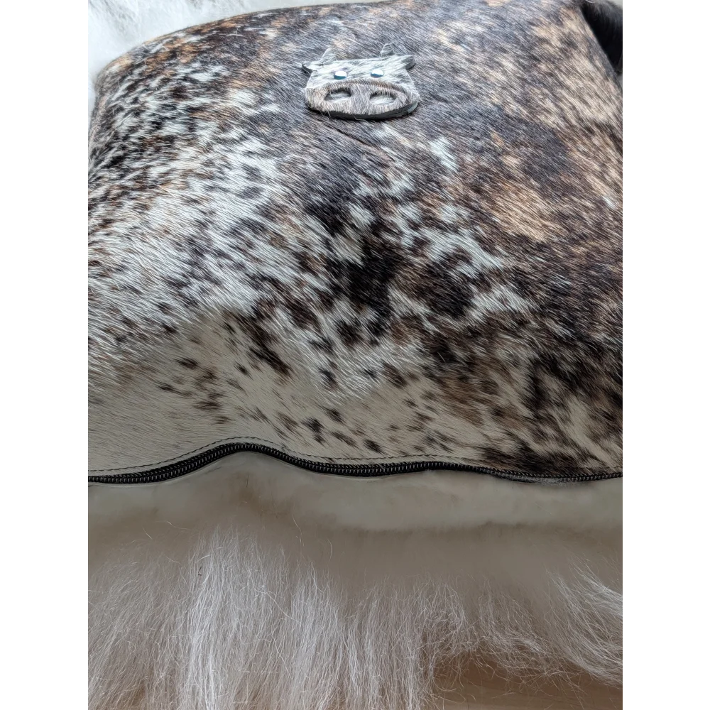 The moo cushion is a brown and white spotted cowhide clutch with a silver pig emblem perfect for angus oliver fans