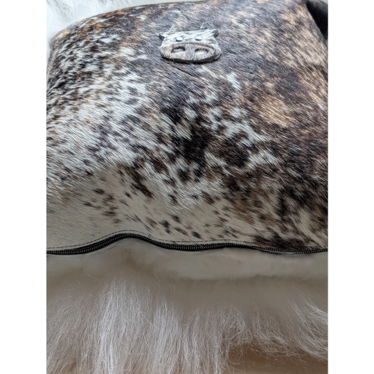 The moo cushion is a brown and white spotted cowhide clutch with a silver pig emblem perfect for angus oliver fans